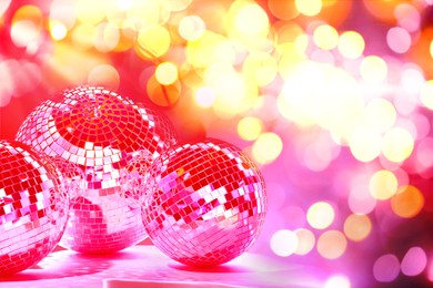 Image of Shiny disco balls on table under golden lights, space for text. Bokeh effect