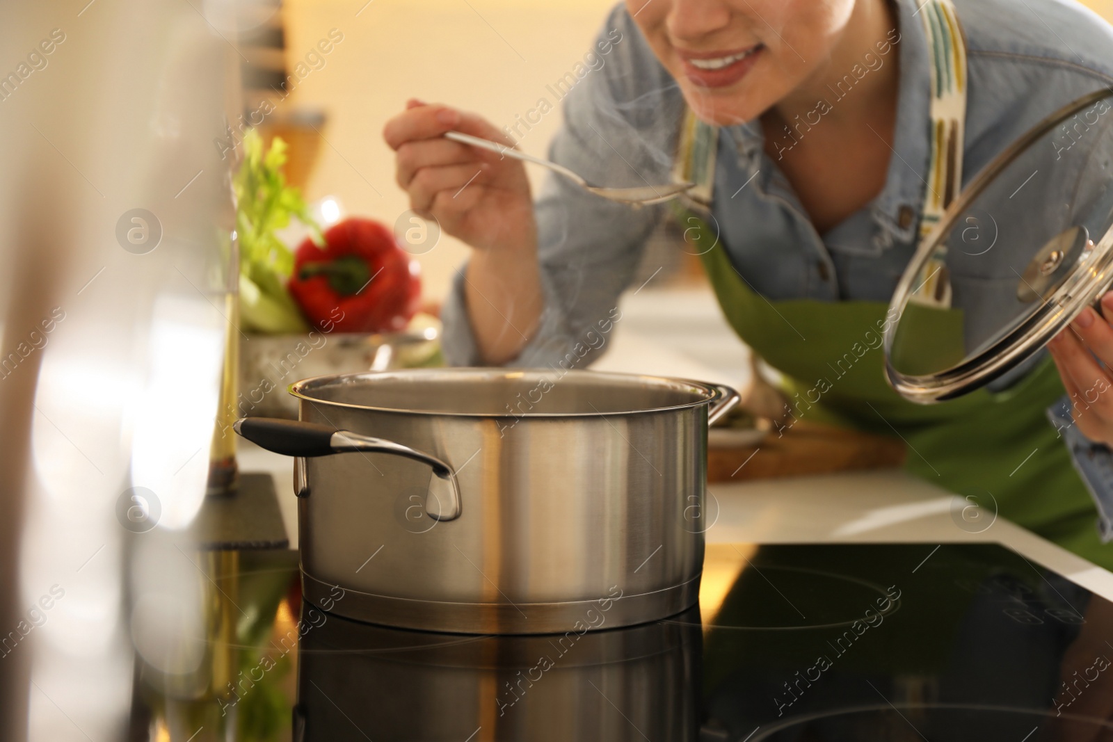 Photo of Woman tasting fresh bouillon in kitchen, closeup. Homemade recipe