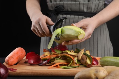 Photo of Woman peeling fresh zucchini at table, closeup