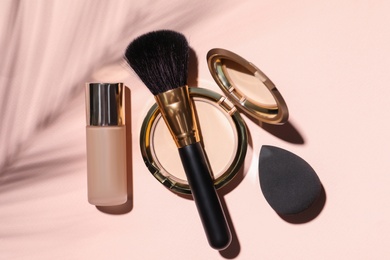 Photo of Liquid foundation, powder, brush and sponge on beige background, flat lay. Makeup products