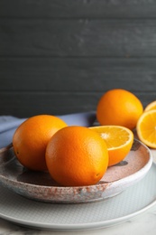 Plate with fresh juicy oranges on marble table