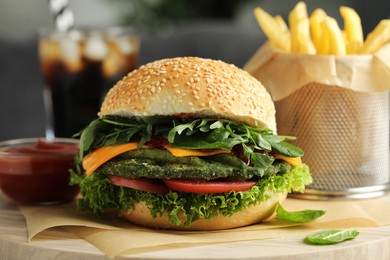 Photo of Tasty vegetarian burger with spinach cutlet, cheese and vegetables served on white table, closeup