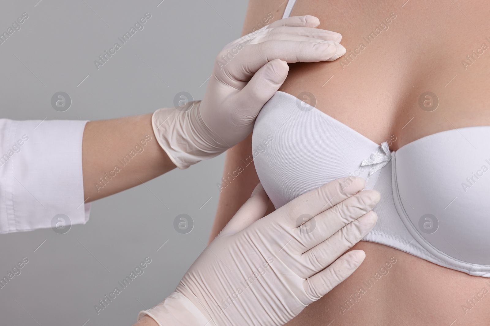 Photo of Mammologist checking woman's breast on gray background, closeup