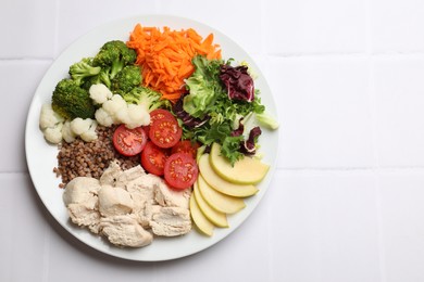 Photo of Balanced diet and healthy foods. Plate with different delicious products on white tiled table, top view. Space for text