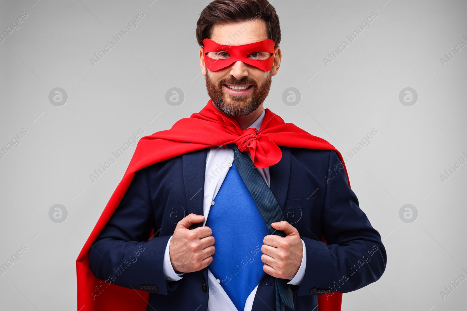 Photo of Happy businessman wearing superhero costume under suit on beige background