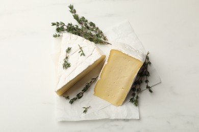 Pieces of tasty camembert cheese and thyme on white table, top view