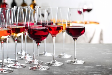 Photo of Glasses with different wines on table against blurred background. Space for text