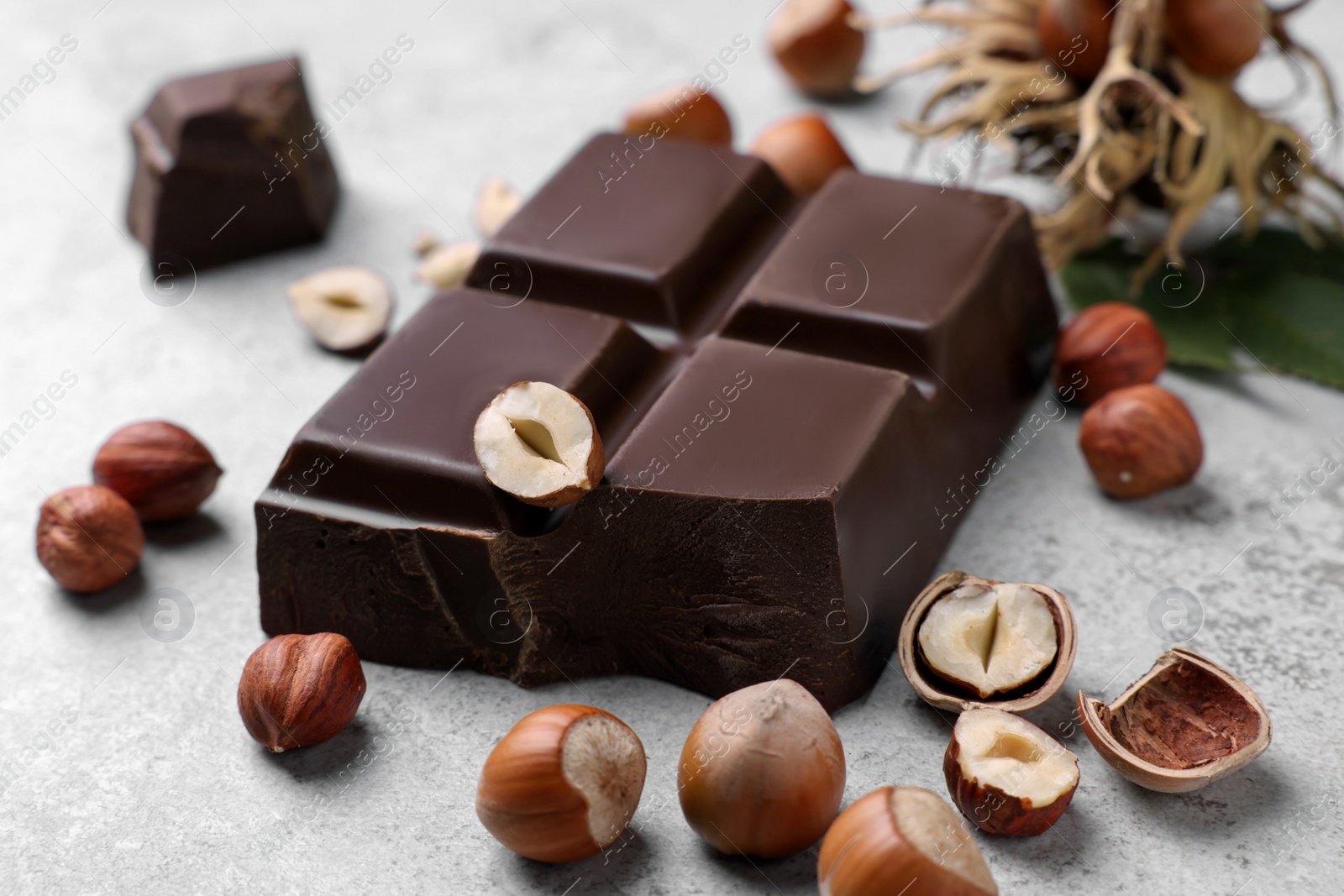 Photo of Delicious chocolate and hazelnuts on light table, closeup