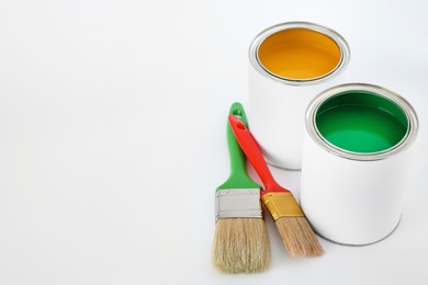 Photo of Open cans of paint with brushes on white background