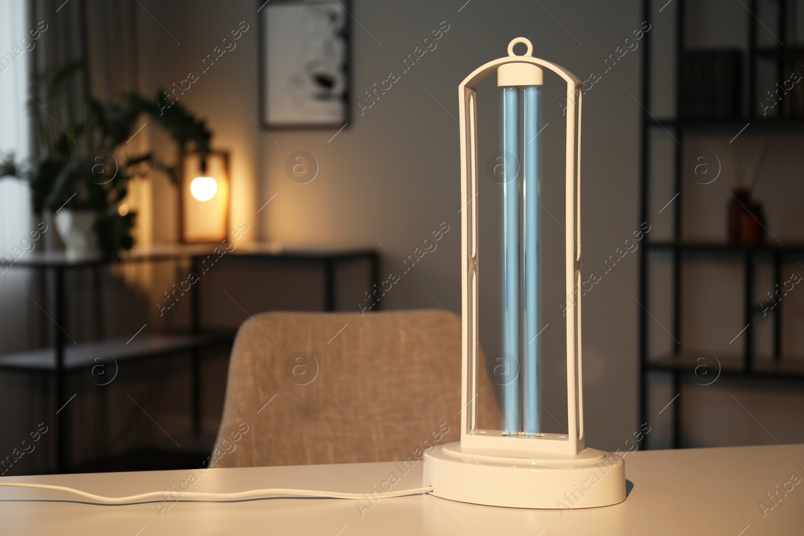 Photo of UV sterilizer lamp on table at home. Space for text