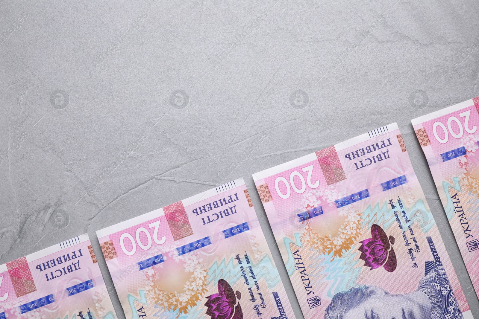 Photo of Ukrainian money on grey background, flat lay. Space for text