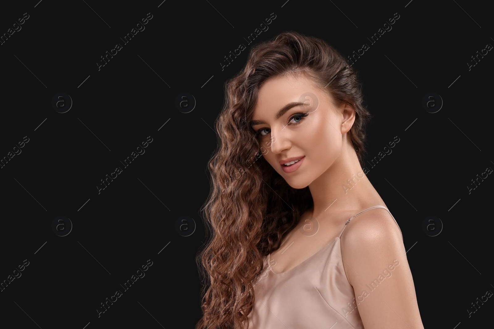 Photo of Beautiful young woman with long curly brown hair on black background, space for text