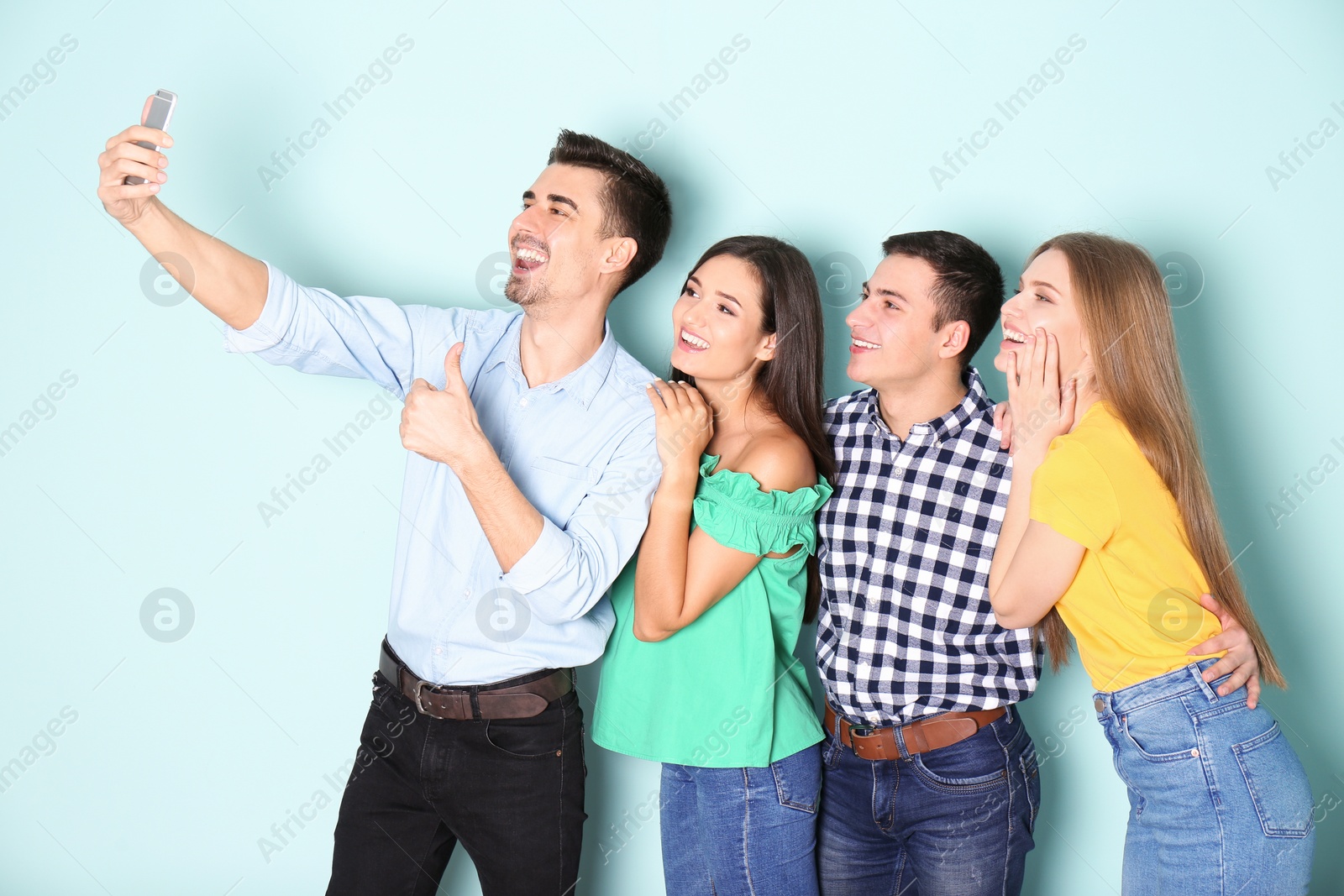 Photo of Young happy friends taking selfie against color background