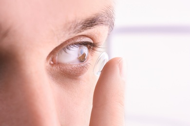 Photo of Young man putting contact lens in his eye, closeup