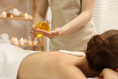 Aromatherapy. Woman receiving back massage with oil in spa salon, closeup