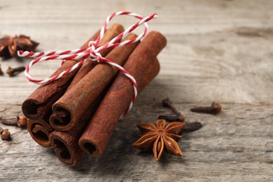 Different spices. Aromatic cinnamon sticks, anise star and clove seeds on wooden table, closeup. Space for text