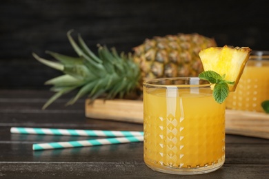 Photo of Glass with delicious pineapple juice on table