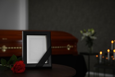 Black photo frame and red rose on table in funeral home