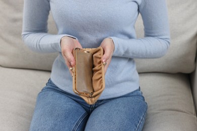 Photo of Woman with empty wallet on sofa indoors, closeup