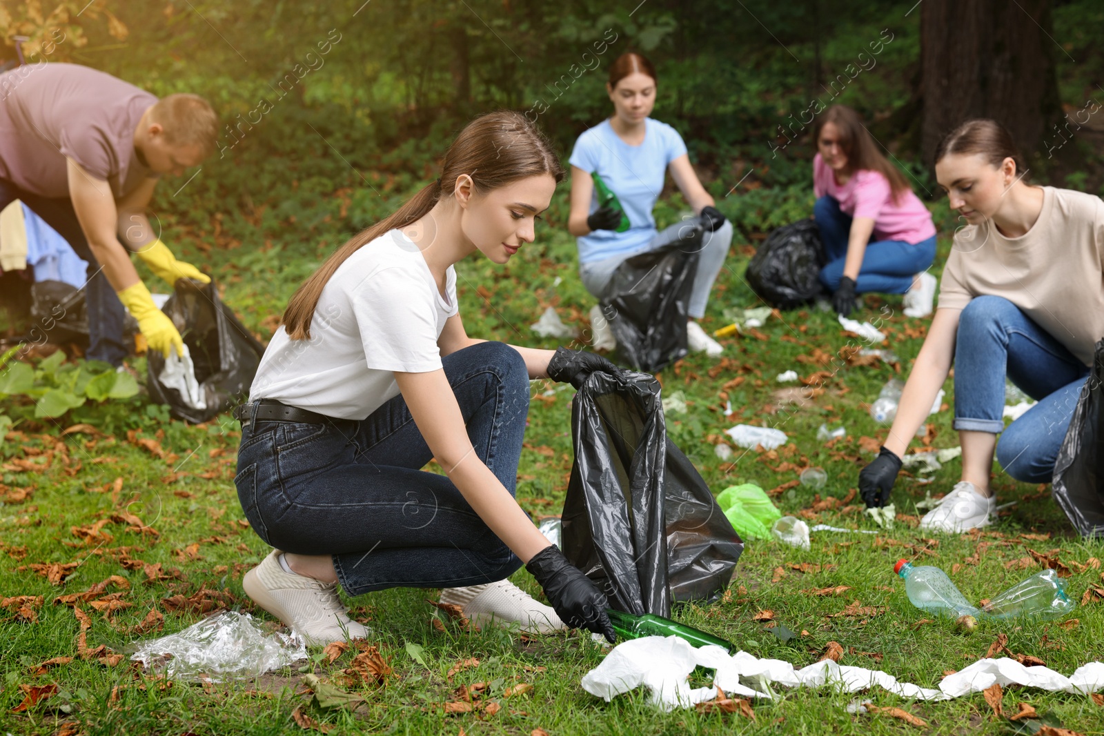 Photo of Group of people with plastic bags collecting garbage in park