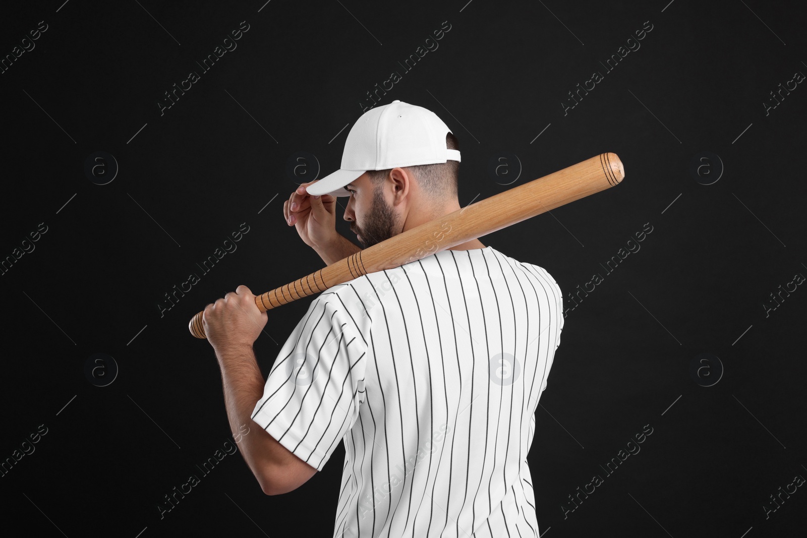 Photo of Man in stylish white baseball cap holding bat on black background