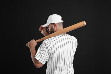 Photo of Man in stylish white baseball cap holding bat on black background