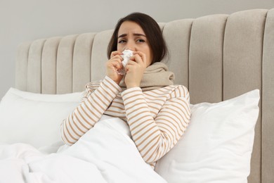 Sick young woman with tissue in bed at home