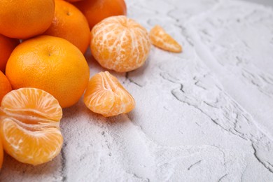 Photo of Fresh juicy tangerines on white textured table, space for text