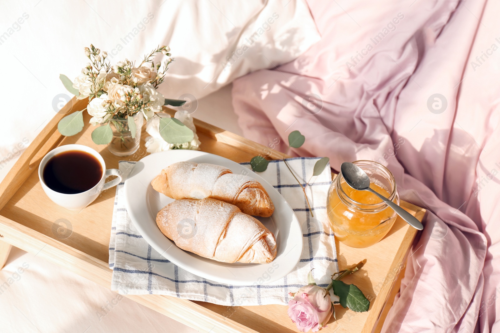 Photo of Tray with delicious croissants, cup of coffee and honey on bed