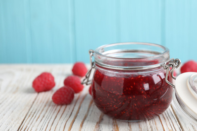 Delicious jam and fresh raspberries on white wooden table. Space for text