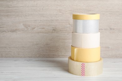 Photo of Many different rolls of adhesive tape on wooden table. Space for text