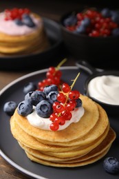 Photo of Tasty pancakes with natural yogurt, blueberries and red currants on wooden table