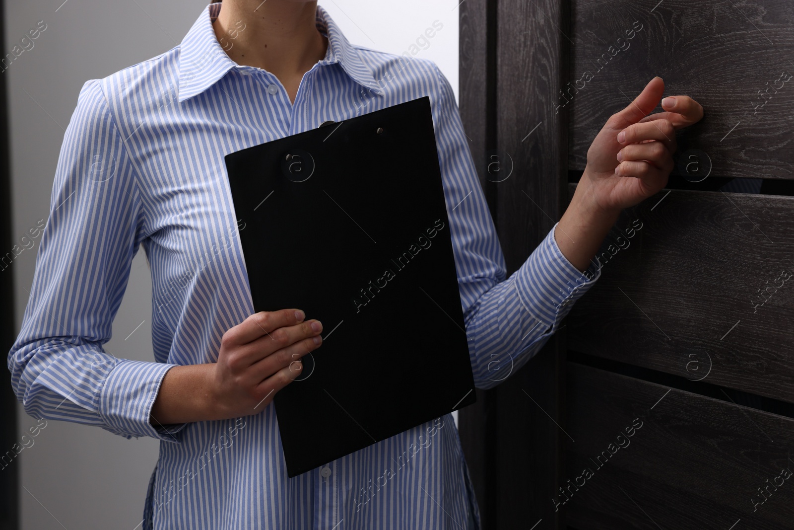 Photo of Collector with clipboard knocking on door indoors, closeup