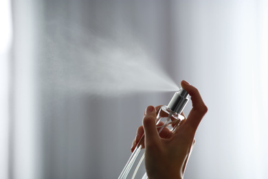 Photo of Woman spraying air freshener indoors closeup. Space for text
