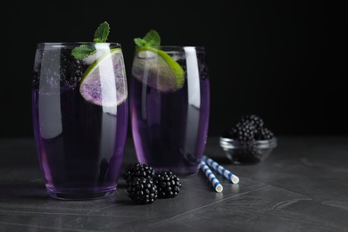 Delicious blackberry lemonade made with soda water and ingredients on grey table, closeup