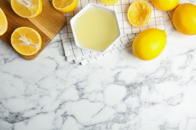 Photo of Freshly squeezed lemon juice on white marble table, flat lay. Space for text