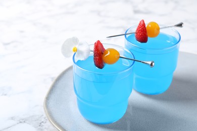 Photo of Bright light blue cocktail in glasses on white marble table