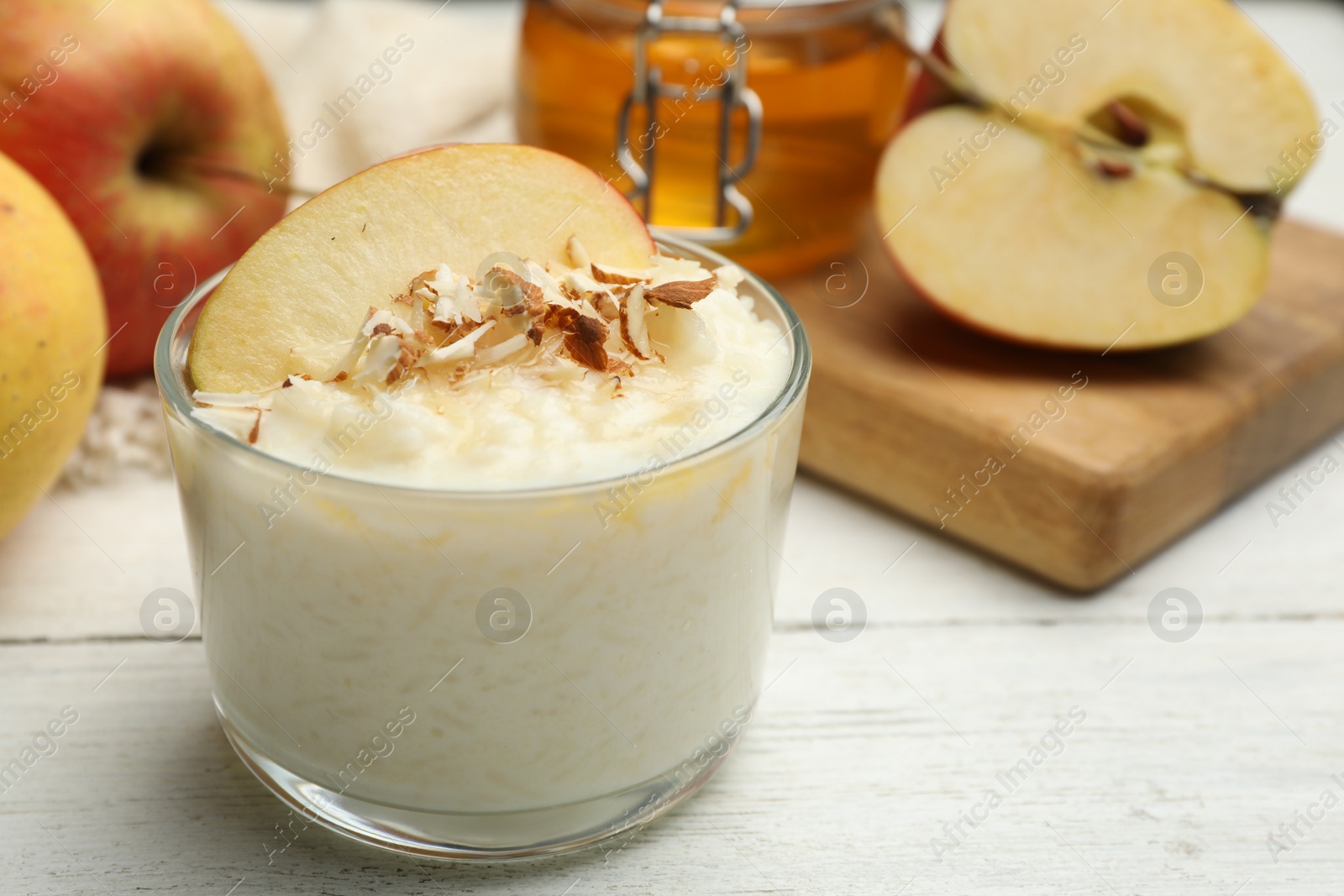 Photo of Delicious rice pudding with apple and almond on white wooden table, closeup