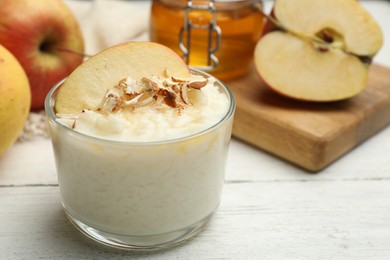 Photo of Delicious rice pudding with apple and almond on white wooden table, closeup
