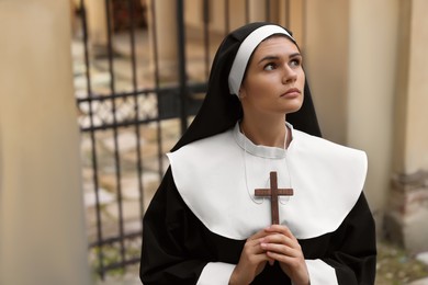 Photo of Young nun with Christian cross near building outdoors