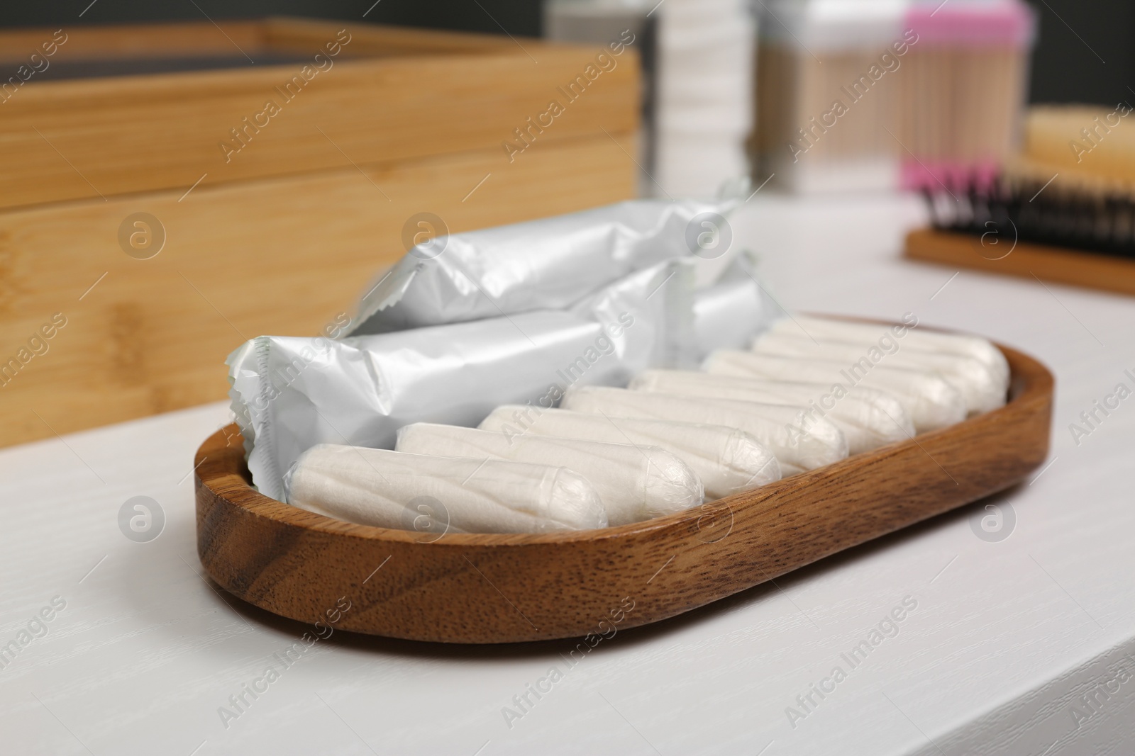 Photo of Wooden tray with many tampons on white table, closeup. Menstrual hygienic product