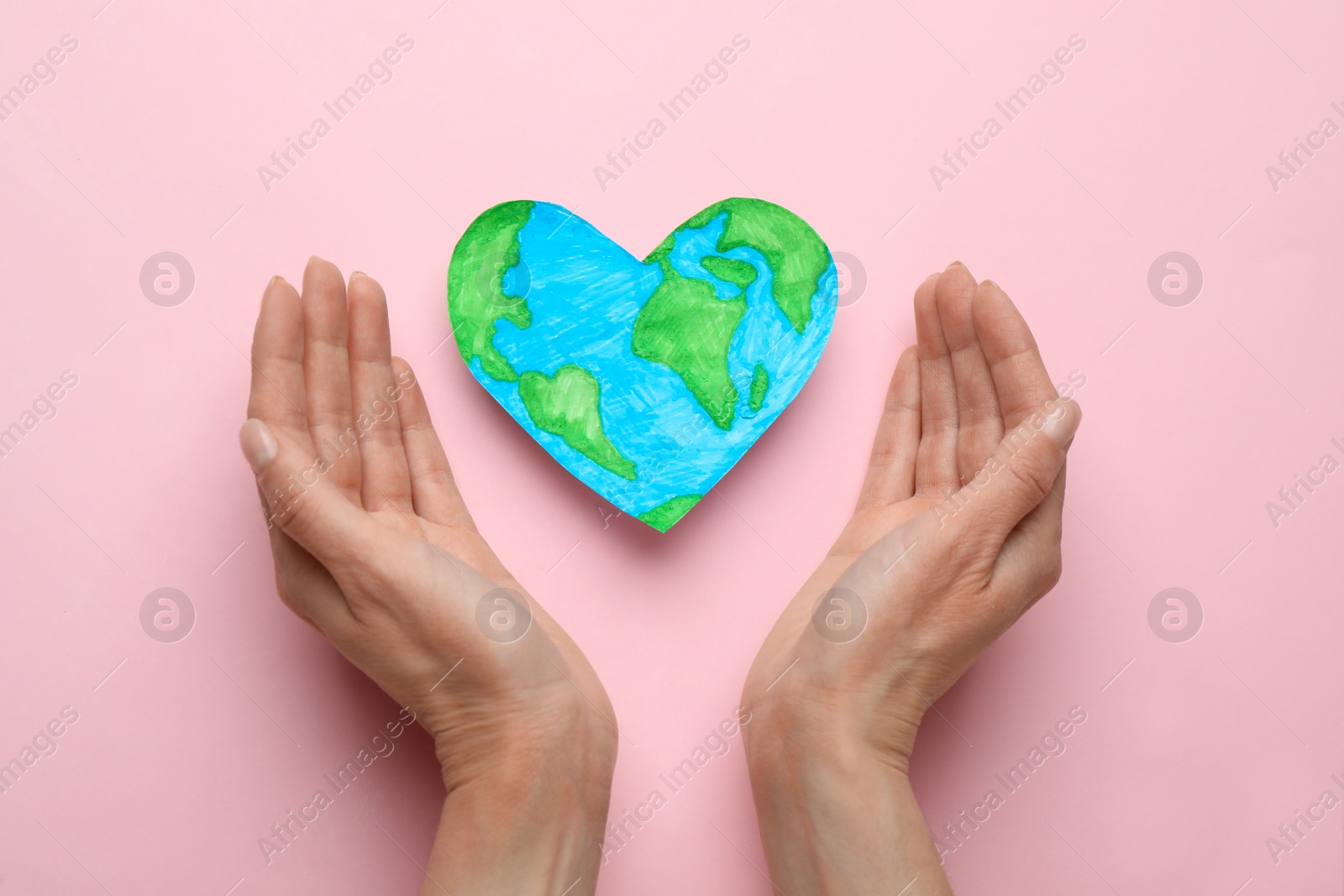 Photo of Woman and heart shaped model of planet on pink background, flat lay. Earth Day