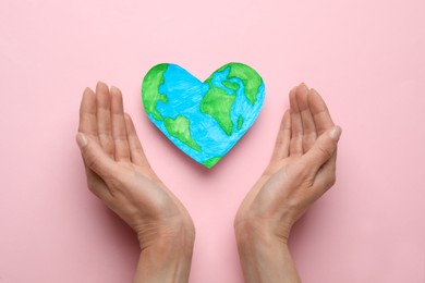 Photo of Woman and heart shaped model of planet on pink background, flat lay. Earth Day