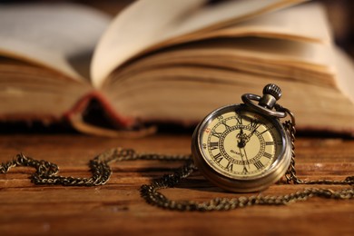 Photo of Pocket clock with chain on wooden table, closeup. Space for text