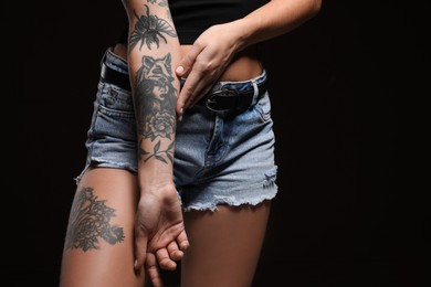 Photo of Woman with tattoos on body against black background. Space for text