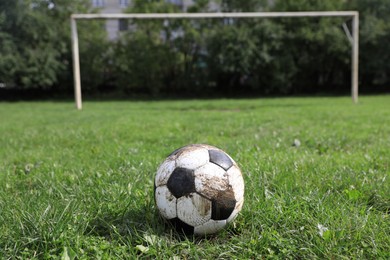 Photo of Dirty soccer ball on green grass outdoors, space for text