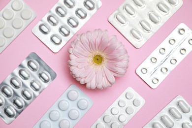 Photo of Many gynecological pills and gerbera flower on pink background, flat lay