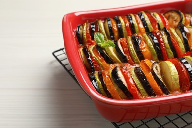 Photo of Delicious ratatouille in baking dish on white wooden table, closeup