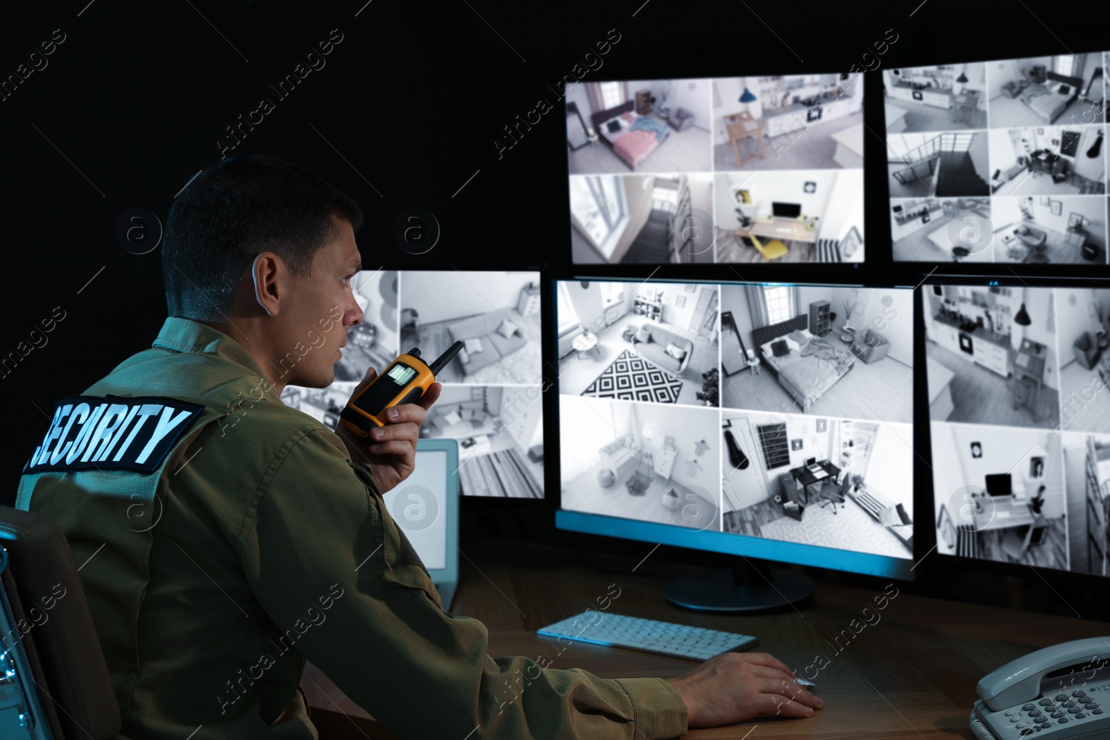 Photo of Security guard with portable transmitter monitoring modern CCTV cameras indoors