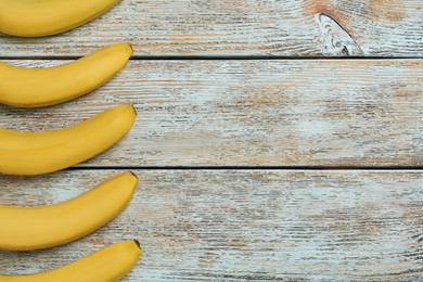 Photo of Ripe yellow bananas on light wooden table, flat lay. Space for text